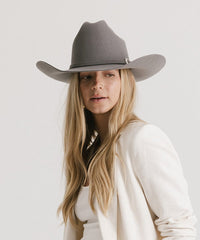 Woman wearing a gray cowboy hat against a white background
