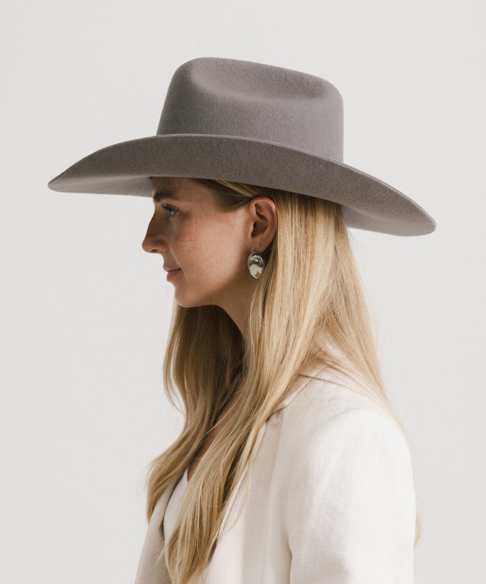 Woman wearing a gray wide-brimmed hat against a white background