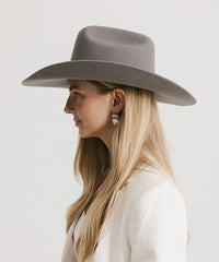 Woman wearing a gray wide-brimmed hat against a white background