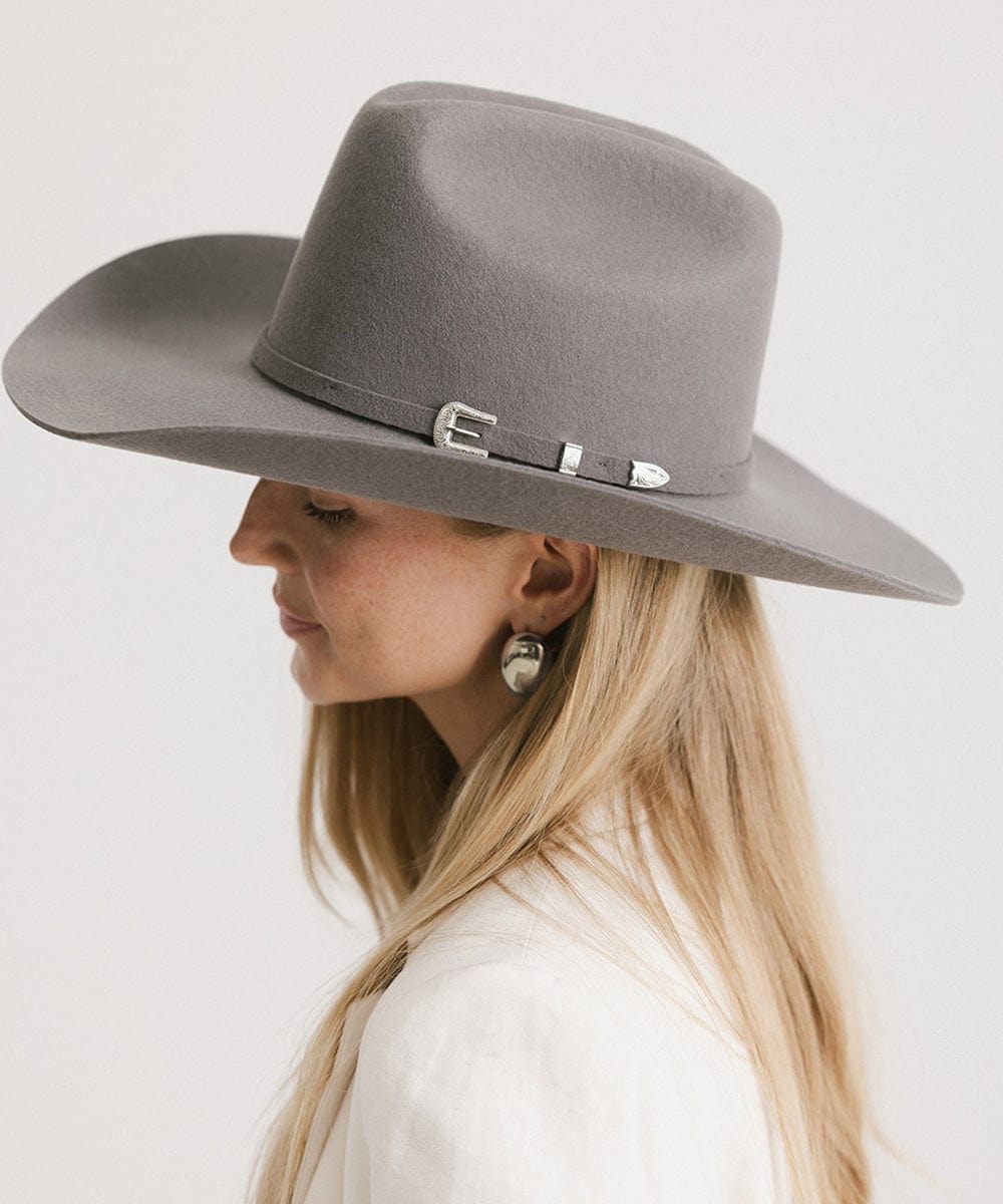 Woman wearing a gray wide-brimmed hat with a decorative band on a white background