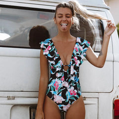 Woman in a floral swimsuit standing in front of a vintage van.