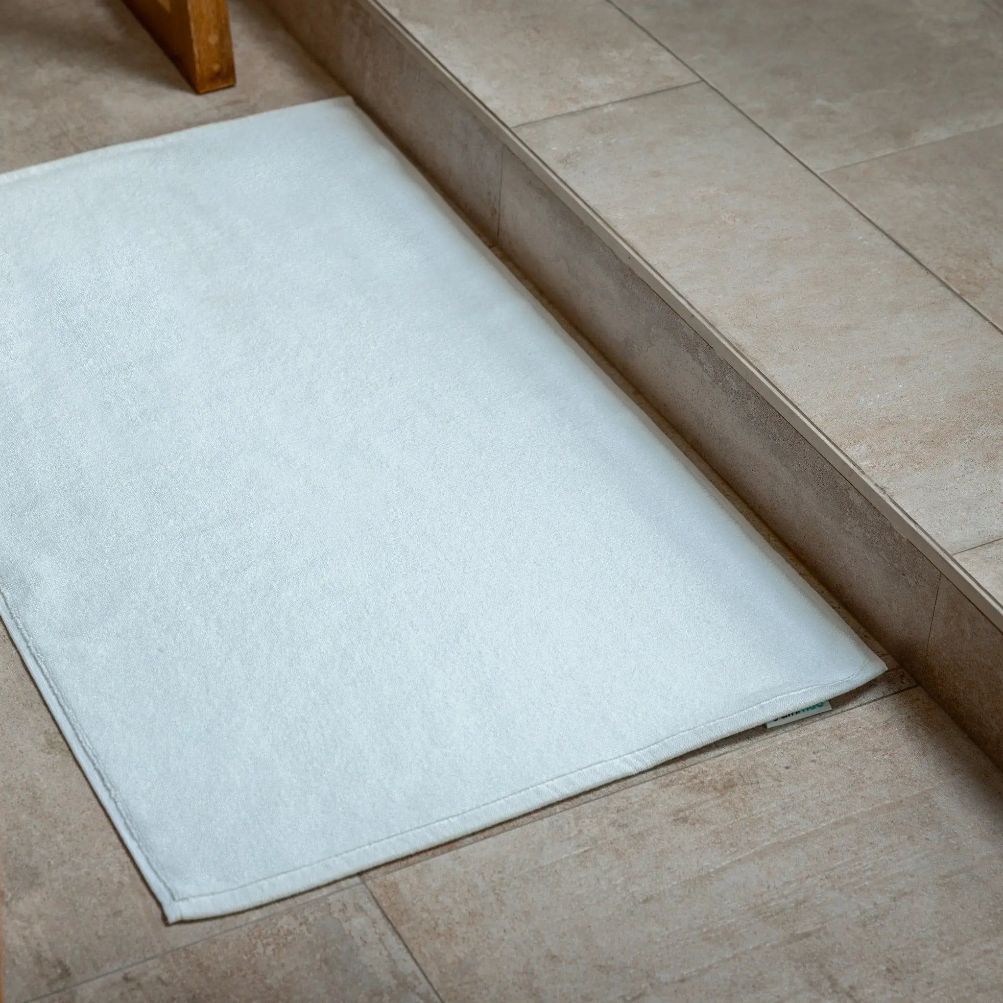 White bath mat on a tiled bathroom floor