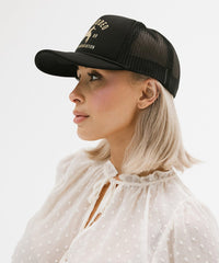 Woman wearing a black cap with mesh back on a white background