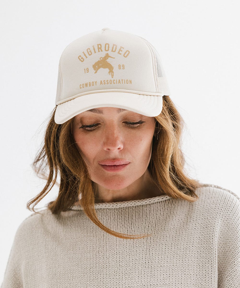 Woman wearing a beige cap with gold text on a white background