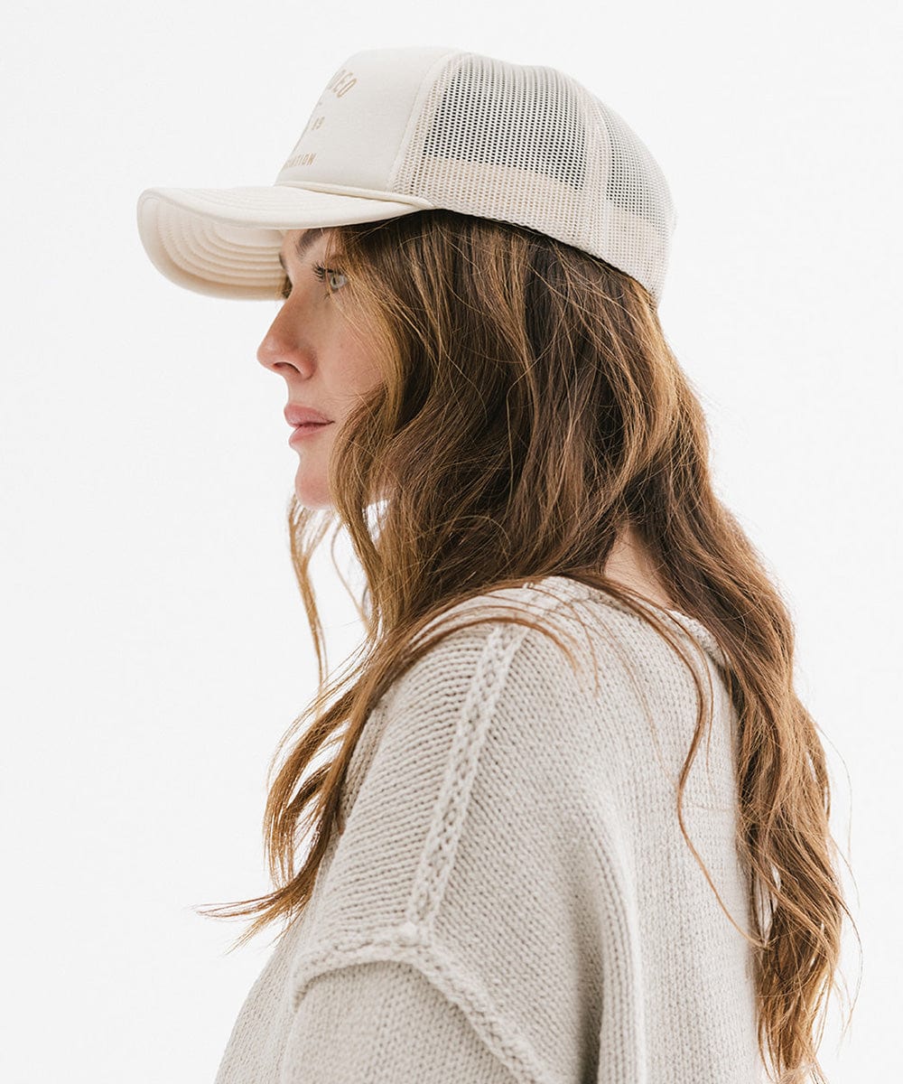 Woman wearing a beige cap and sweater on a white background