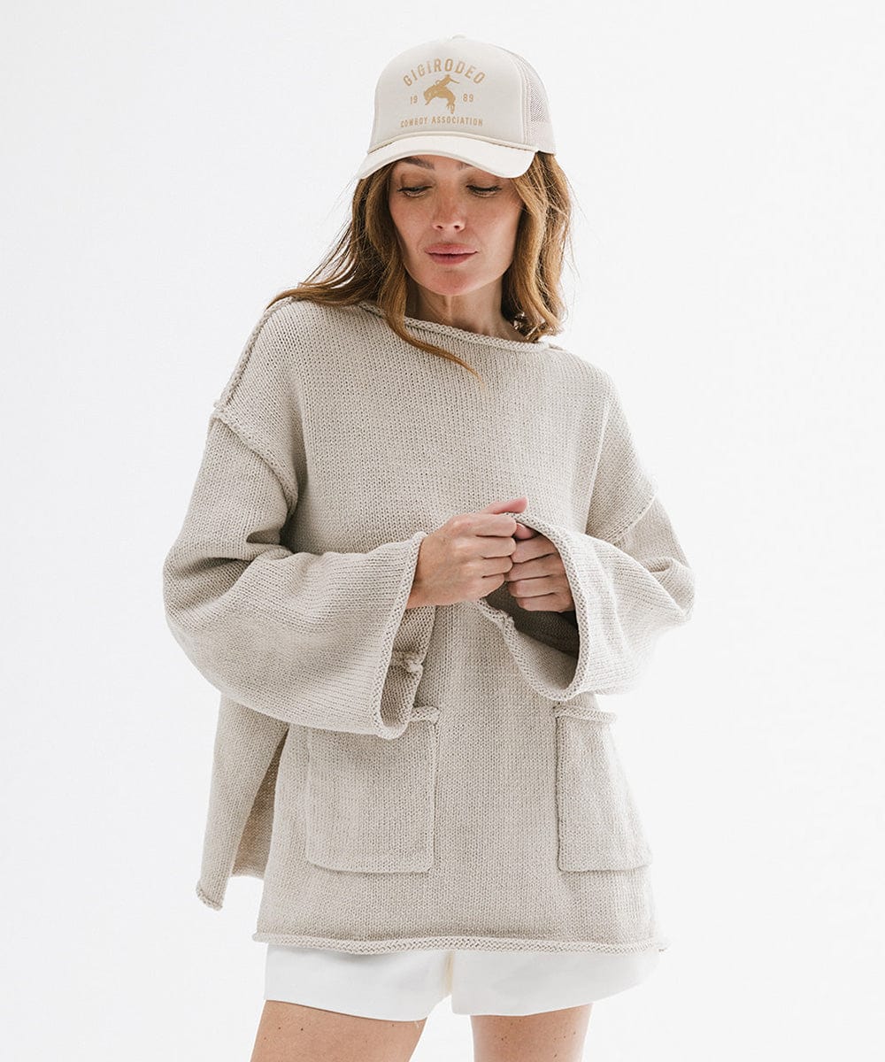Woman wearing a beige sweater and white cap on a white background