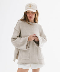 Woman wearing a beige sweater and white cap on a white background