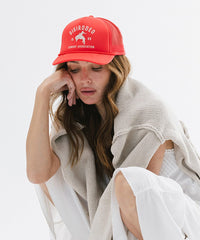 Woman wearing a red cap with text and a logo on a white background