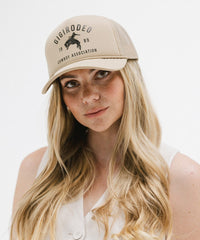 Woman wearing a beige cap with text and graphics on a white background