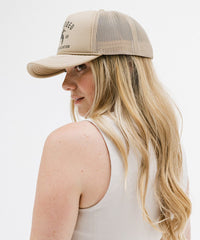 Woman wearing a beige cap with a logo on a white background