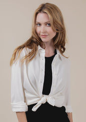 Woman wearing a white blouse with a black top underneath on a beige background