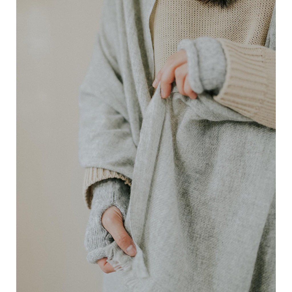 Person wearing a light gray cardigan over a beige sweater with a neutral background