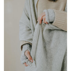 Person wearing a light gray cardigan over a beige sweater with a neutral background