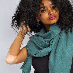 Woman wearing a teal scarf against a plain background