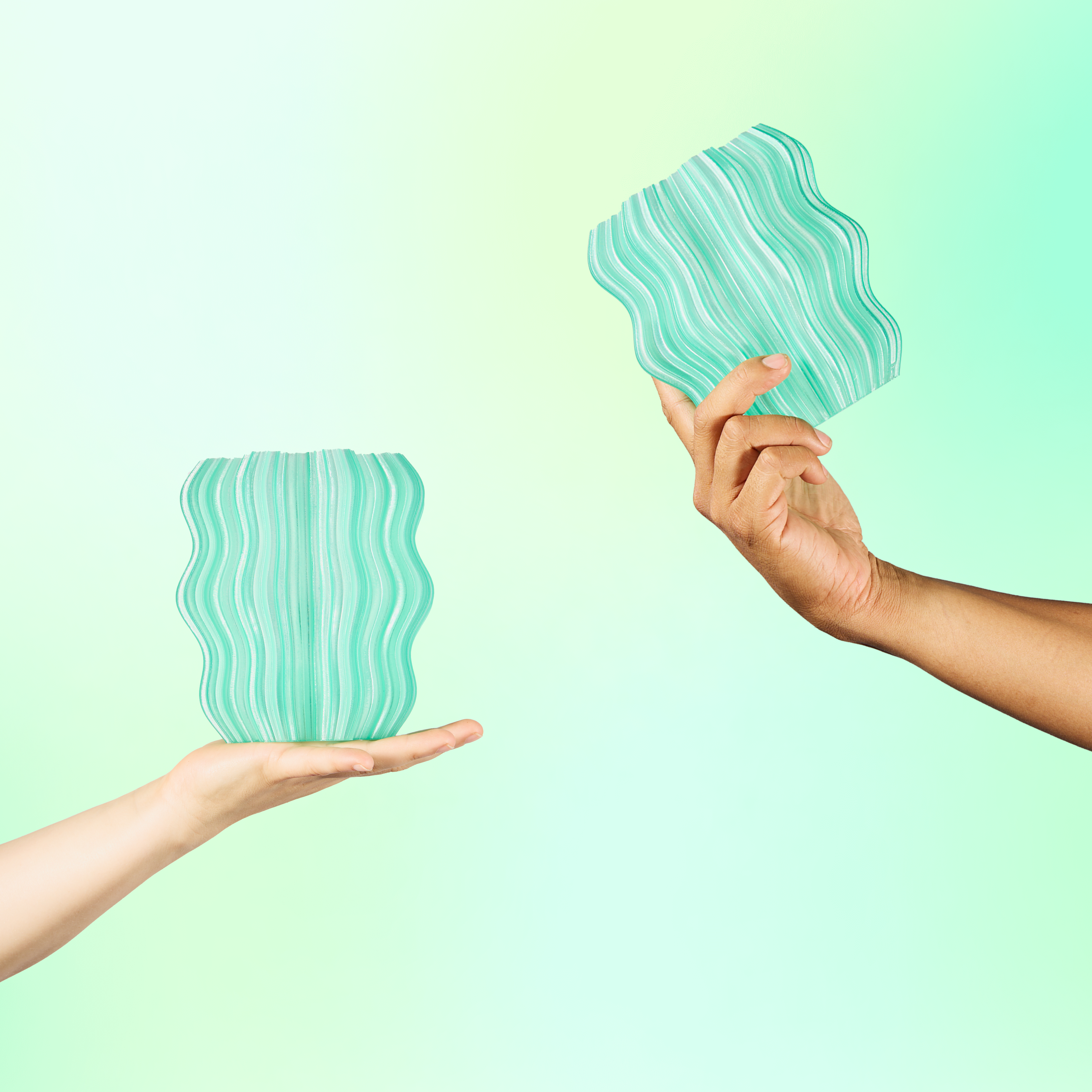 Two hands holding green wavy-patterned objects against a light green background