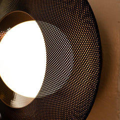Close-up of a light fixture with a mesh cover on a beige wall.