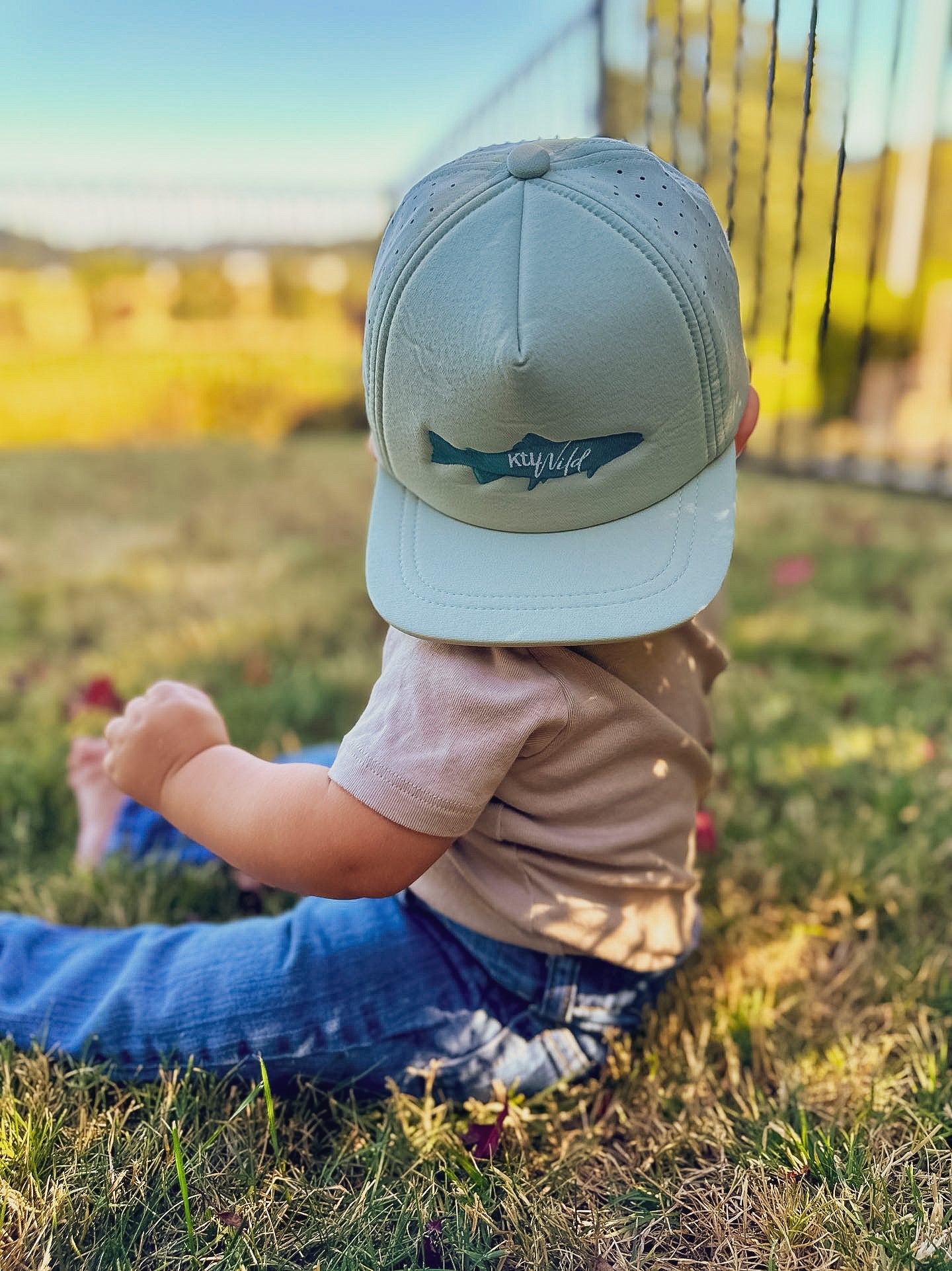 Child wearing a cap with a logo in an outdoor setting