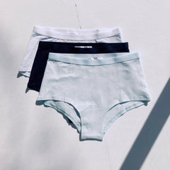 Three pairs of underwear in light blue, black, and white on a light gray background