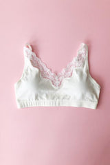 White bra with lace trim on a pink background