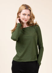 Woman wearing a green long-sleeve top against a beige background