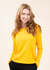 Woman wearing a yellow long-sleeve top against a beige background
