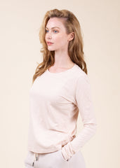 Woman wearing a light pink long-sleeve top against a beige background