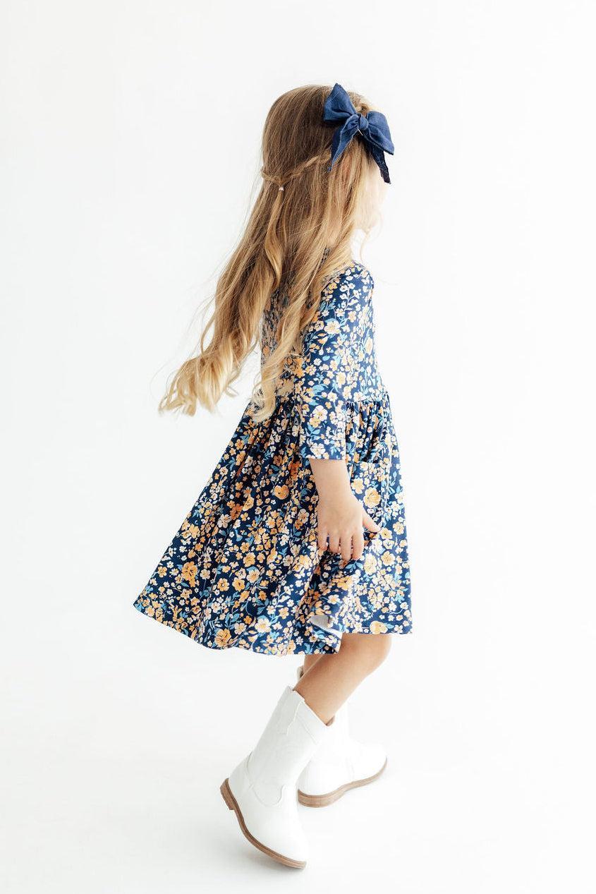 Young girl wearing a floral dress with long sleeves and white boots on a white background