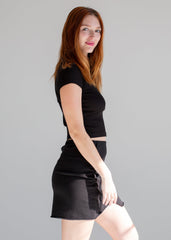 Woman wearing a black outfit against a gray background