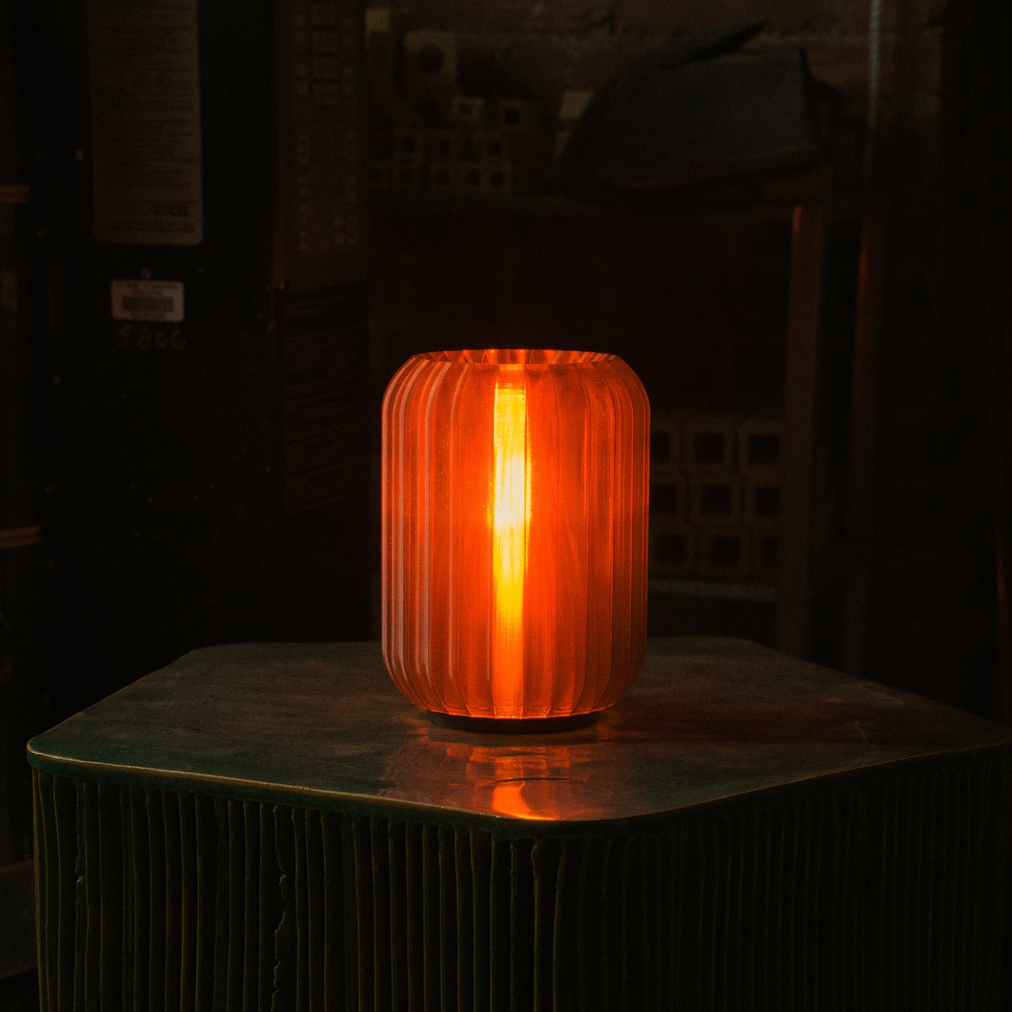 Orange ribbed glass table lamp on a dark surface with a blurred background