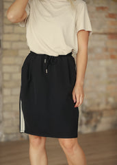 Person wearing a black skirt with white stripes on a brick wall background