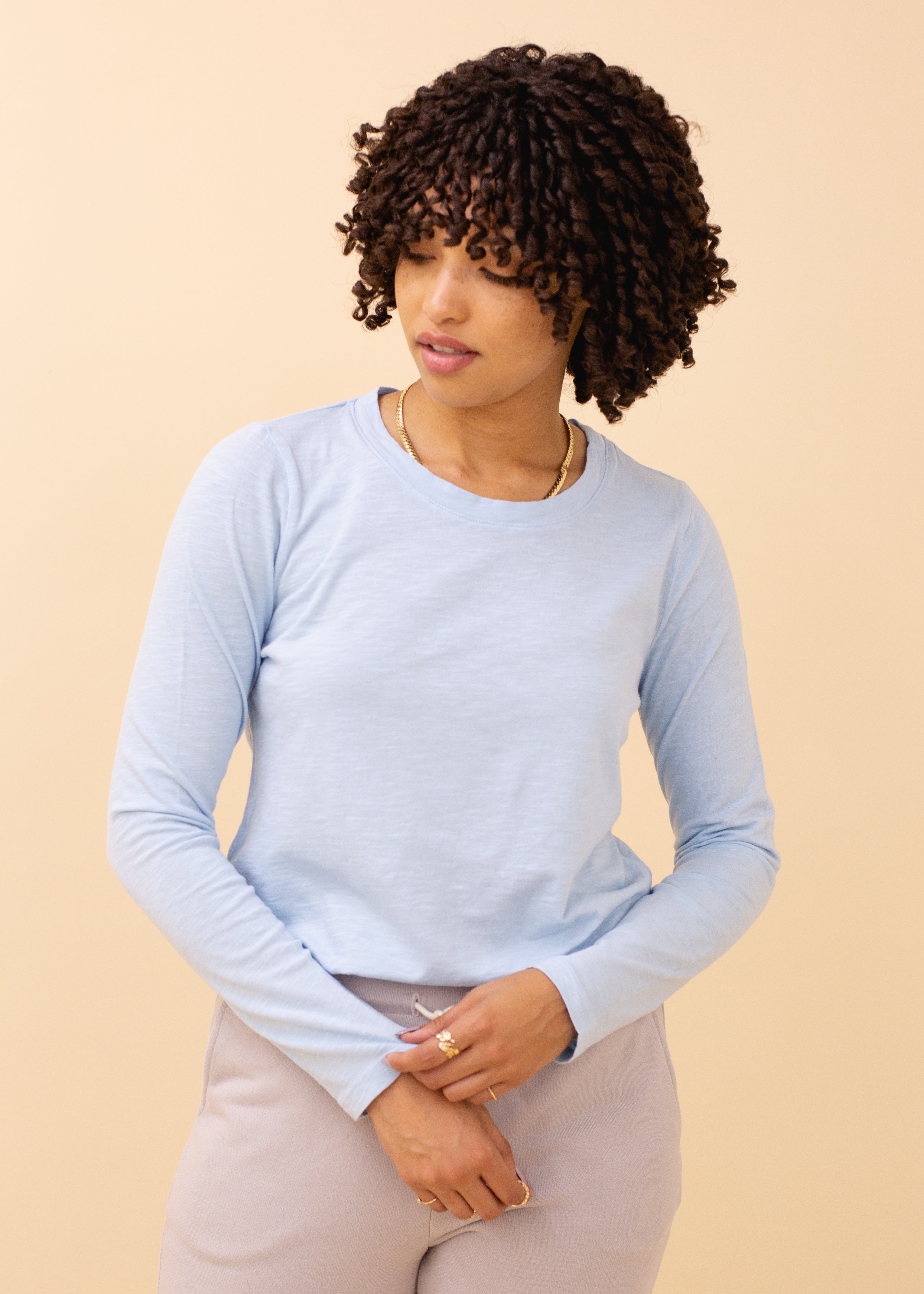 Woman wearing a light blue long-sleeve top against a beige background