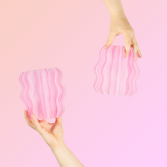 Two hands holding pink wavy plates against a pink background