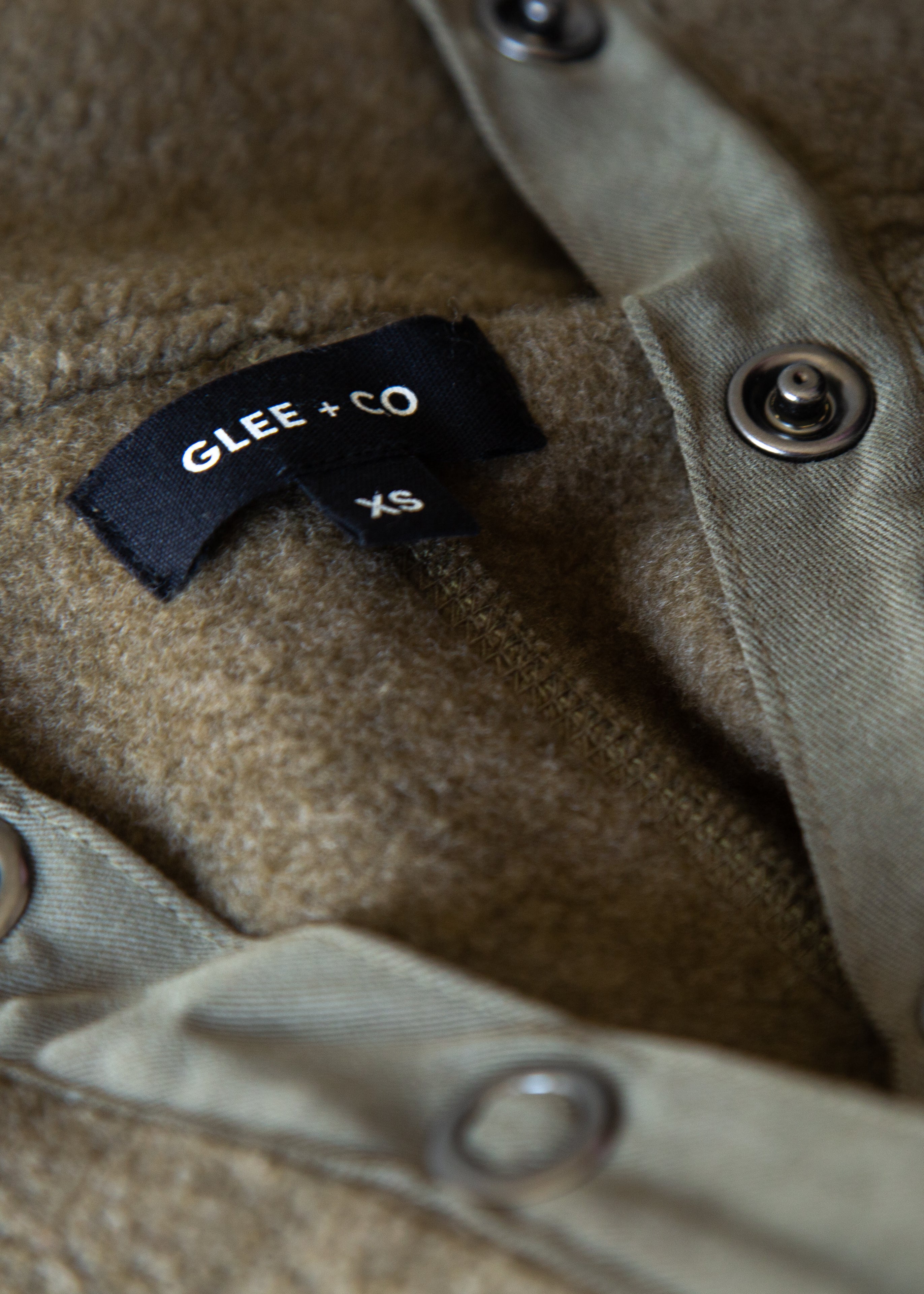 Close-up of a label on a textured fabric surface with 'Glee + Co' branding.