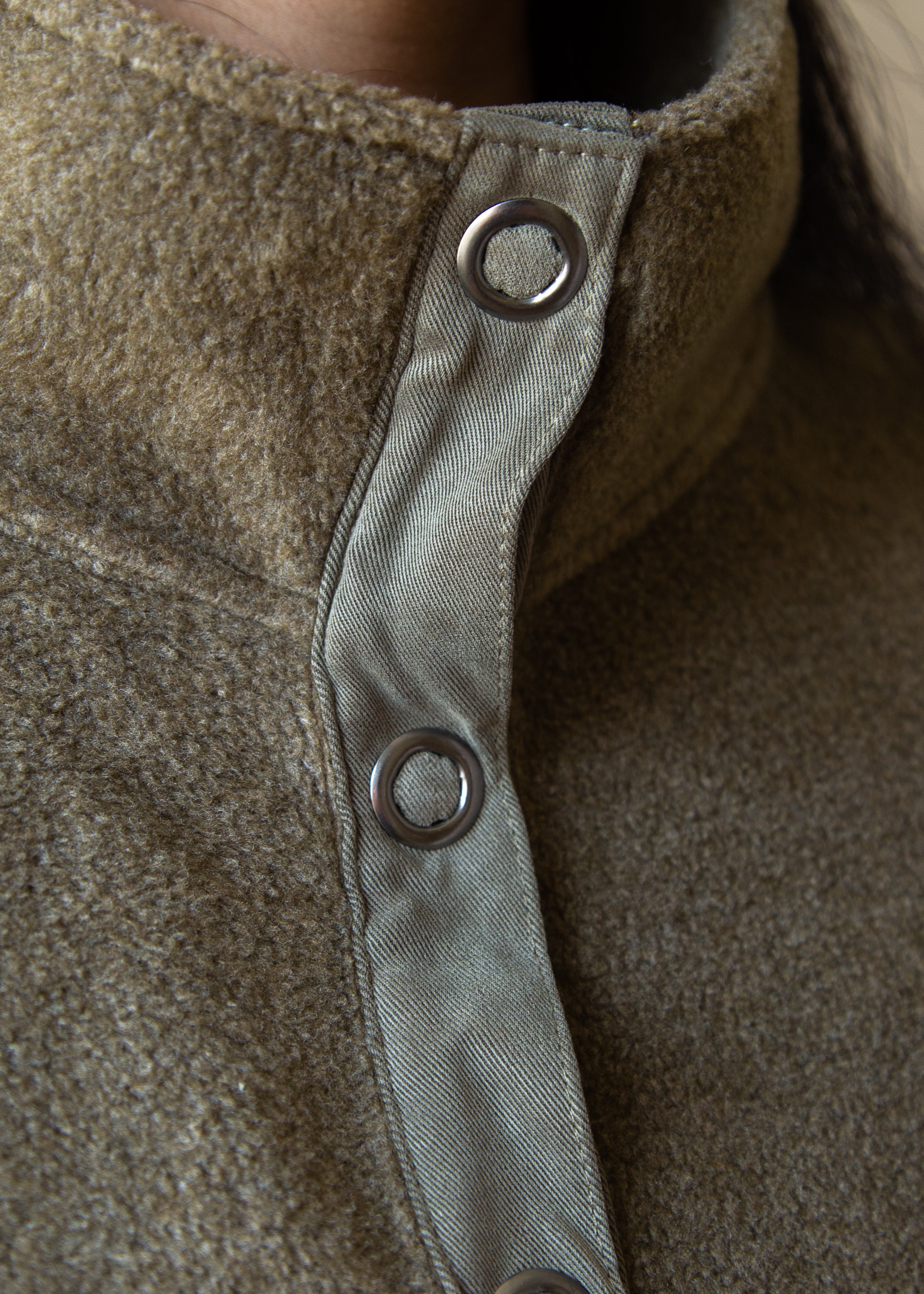 Close-up of a textured fabric with metal buttons on a brown background