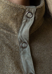 Close-up of a textured fabric with metal buttons on a brown background