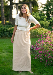 Woman standing outdoors in a garden with greenery and flowers