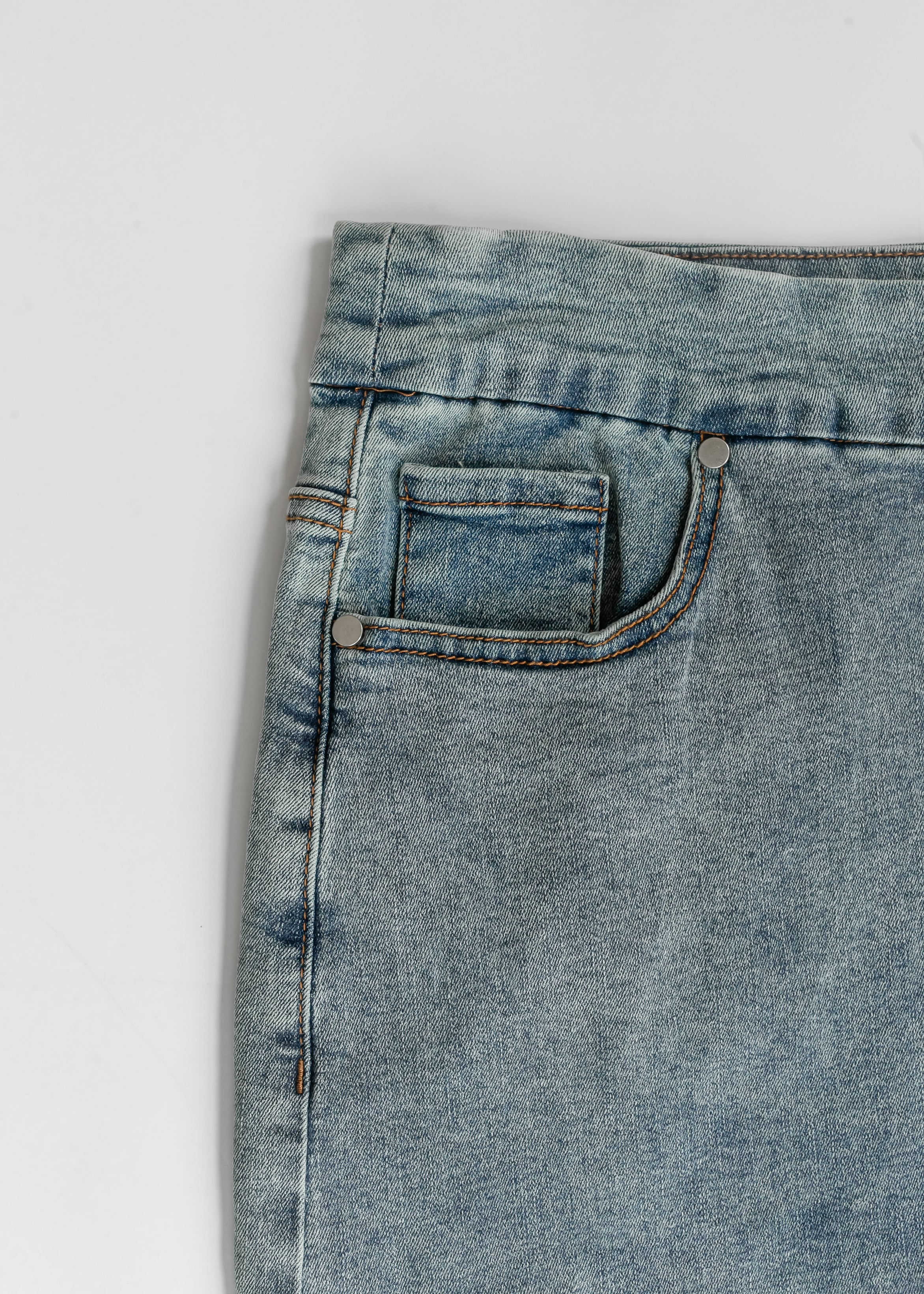Close-up of a blue denim pocket on a white background