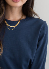 Person wearing a navy blue top with a gold necklace