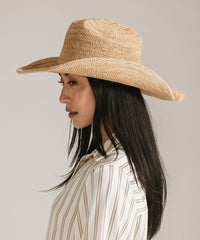 Woman wearing a straw hat against a plain background