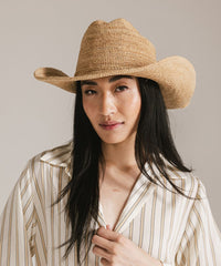 Woman wearing a straw hat against a neutral background