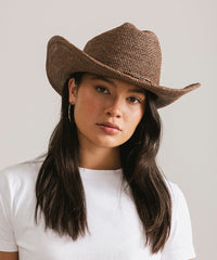 Woman wearing a brown cowboy hat against a plain background