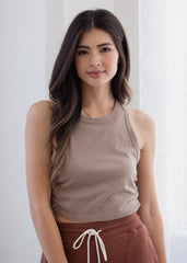 Woman wearing a brown tank top and maroon pants with a white background