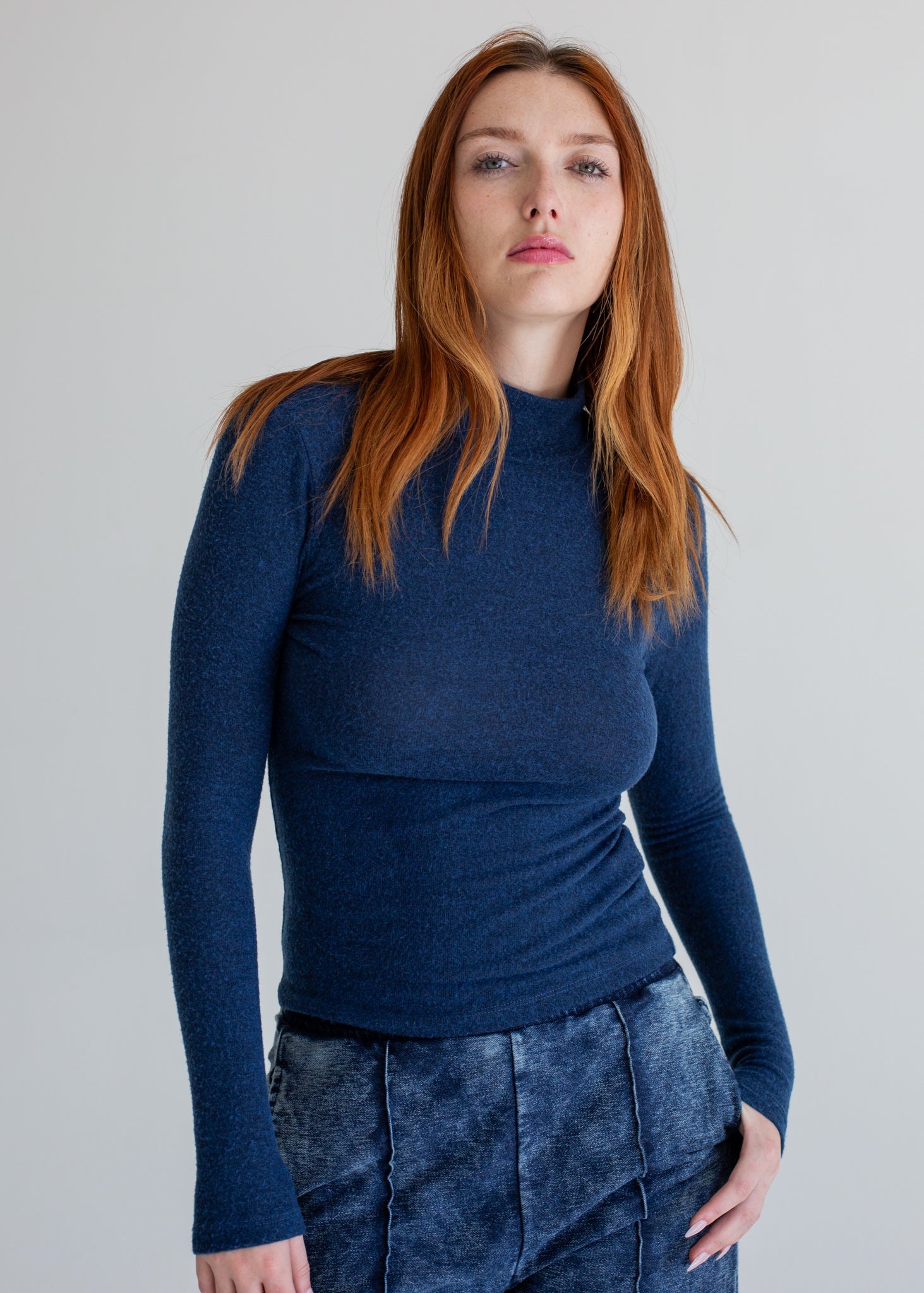 Woman wearing a blue long-sleeve top against a plain background