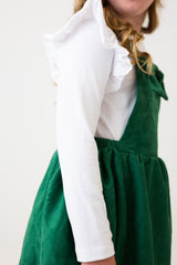 Person wearing a green dress with a white blouse against a plain background
