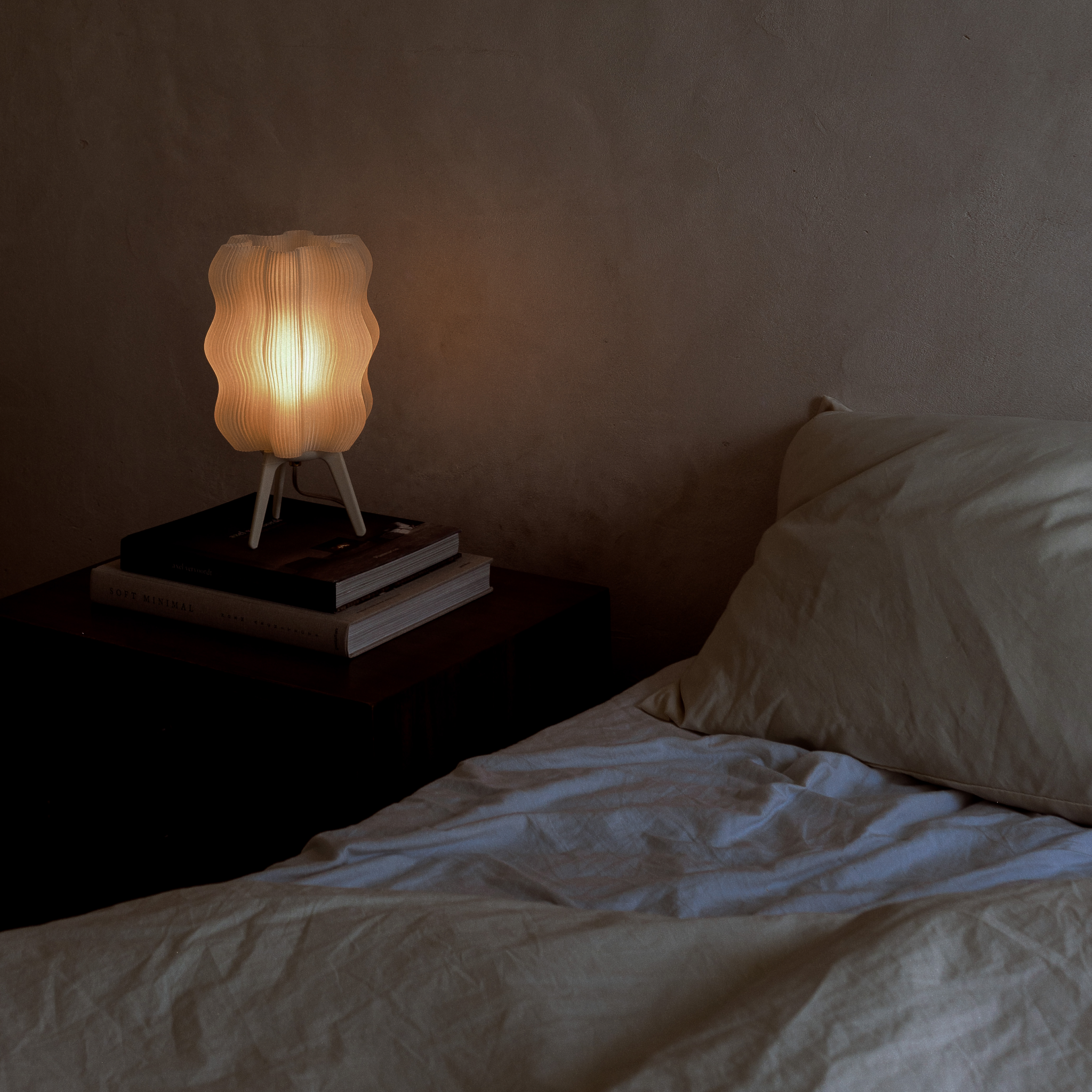 Lamp on a nightstand next to a bed with soft lighting