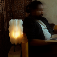 Man sitting in a dimly lit room with a lamp and book
