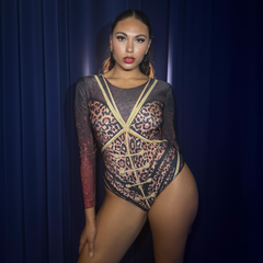 Model wearing a leopard print and sheer long-sleeve bodysuit against a dark blue curtain background.