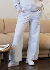 Person wearing a gray tracksuit standing in front of a beige sofa.