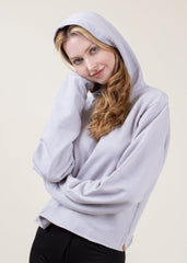 Person wearing a light gray hoodie against a plain background