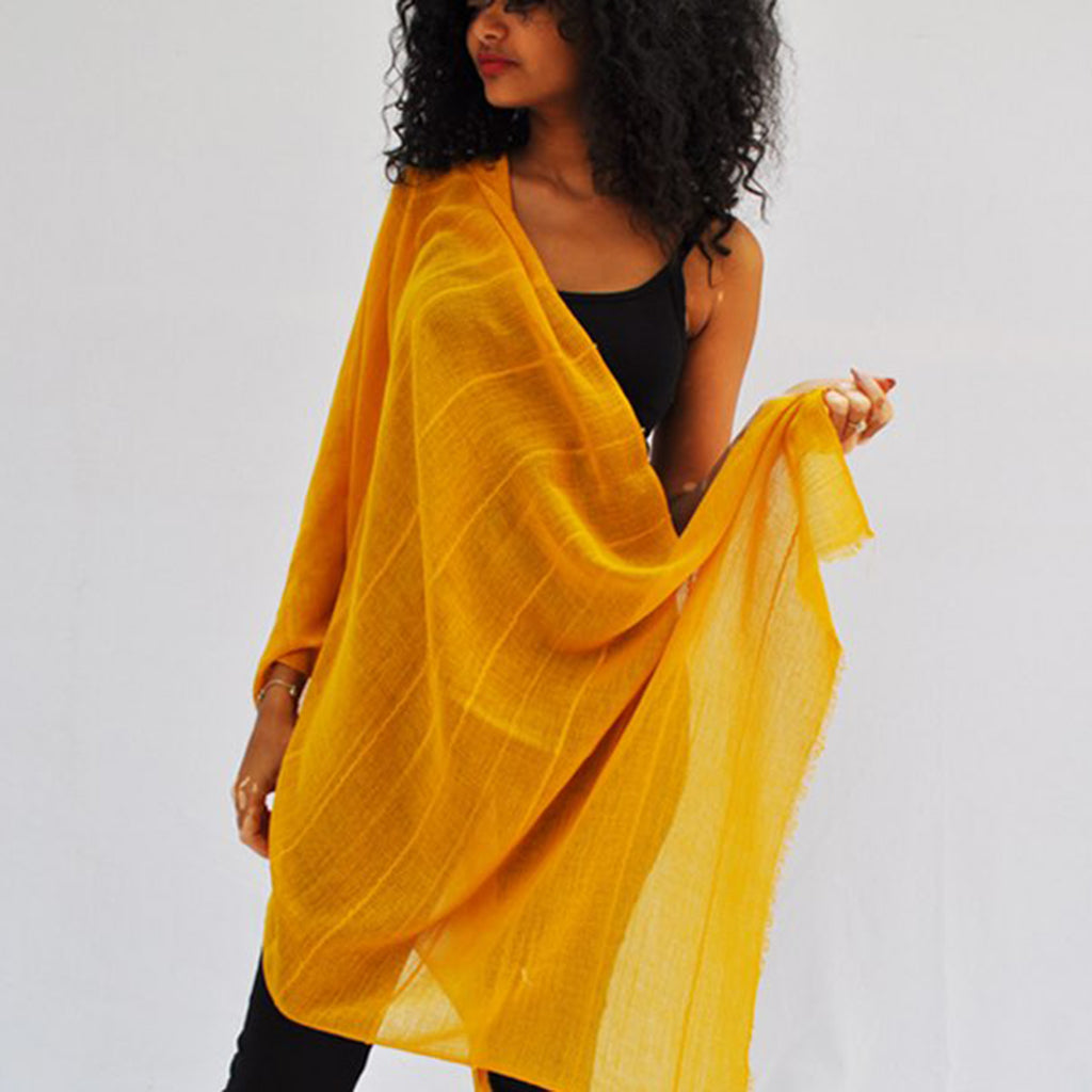 Woman holding a yellow scarf against a white background